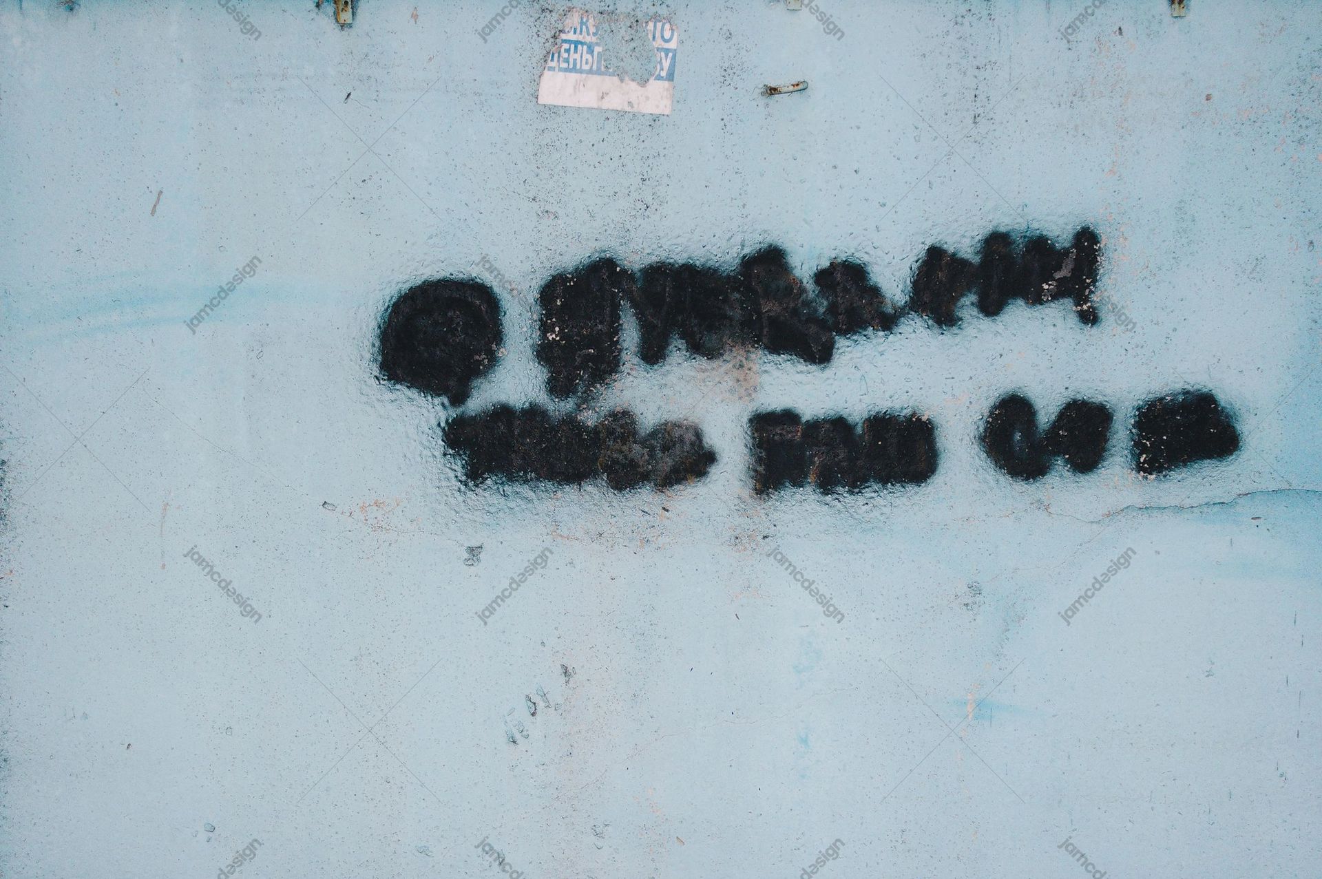 Pale Blue Wall Texture With Black Graffiti. This JPG texture shows black stencil graffiti across a pale blue, weathered wall