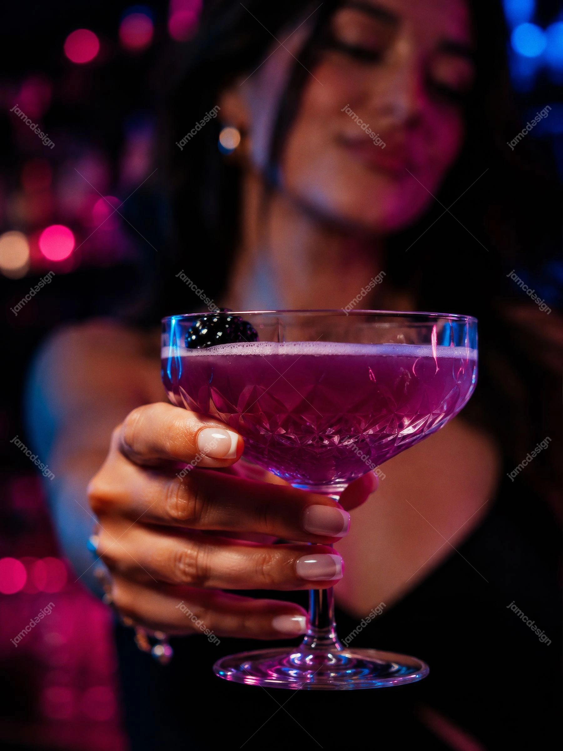Foto De Coquetel Roxo Em Close Com Luzes Neon De Clube Noturno. Foto em JPG mostrando uma mão segurando uma taça de coquetel roxo diante de uma mulher