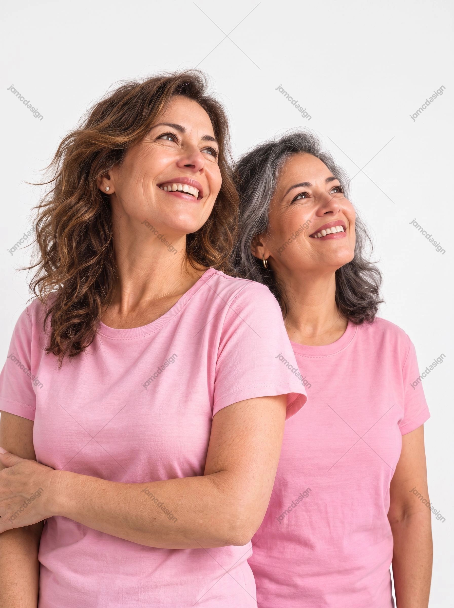 Two Women Smiling In Pink T-Shirts. This JPG photo features two smiling women in pink T shirts, standing together against a clean white studio background