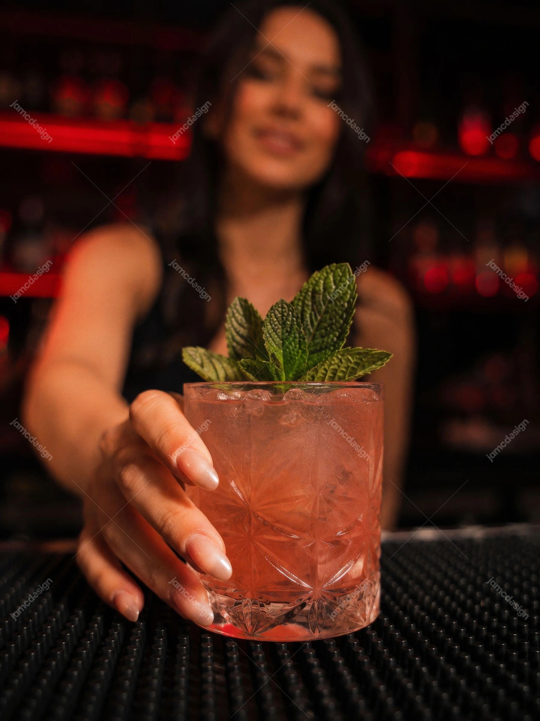 Foto Em Close De Coquetel De Menta No Bar Noturno. Foto JPG em close-up de um coquetel vermelho de menta segurado por uma mulher no balcão escuro