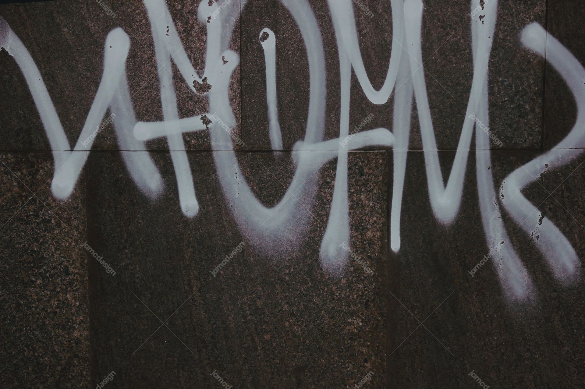 Dark Concrete Wall Texture With Pale Graffiti. This JPG texture shows pale spray painted graffiti across a dark, rough concrete wall