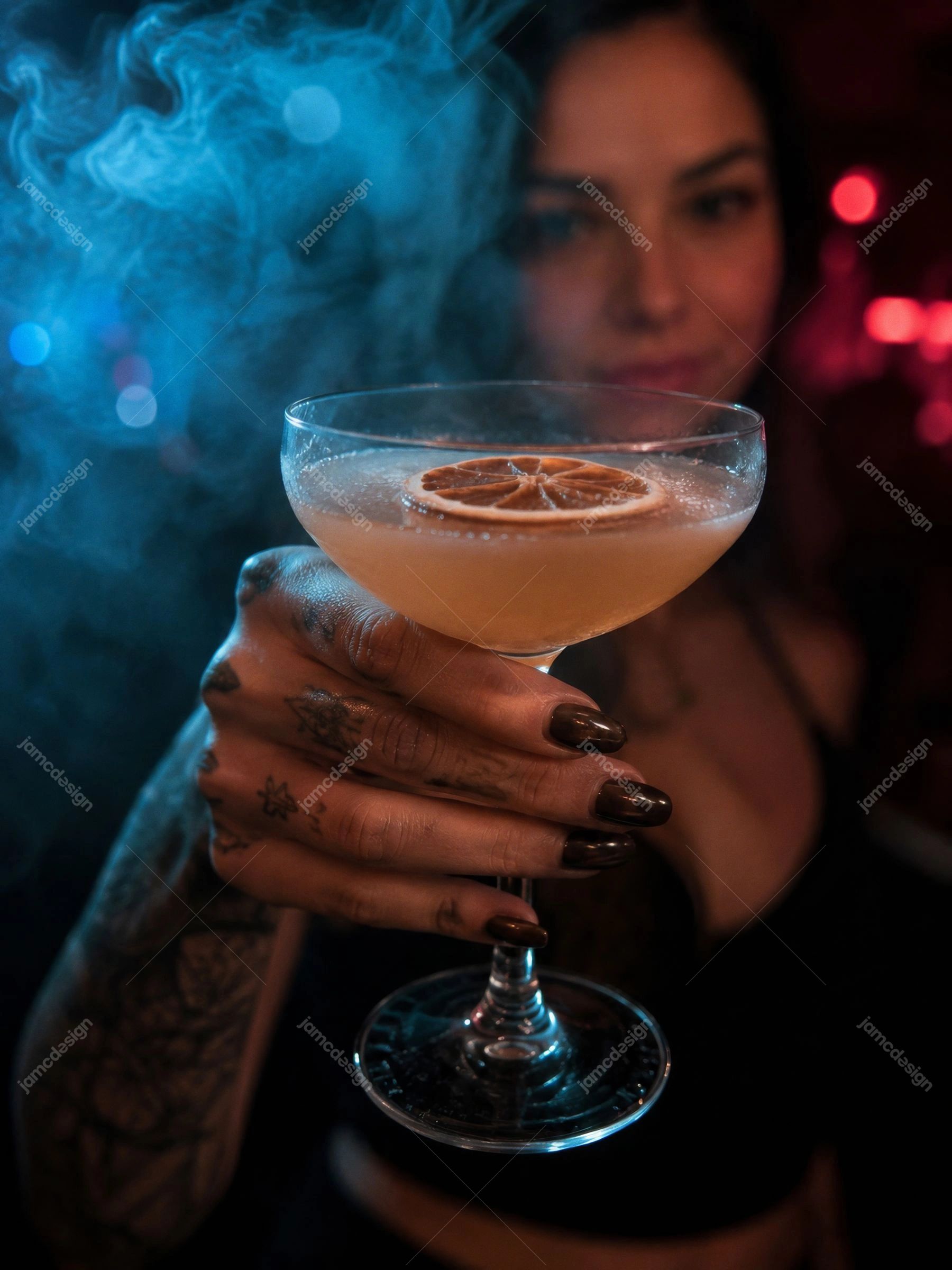 Tattooed Woman Holding Citrus Cocktail In Neon Club Blue Lit Model. JPG photo of a tattooed woman holding a citrus cocktail in a dark nightclub