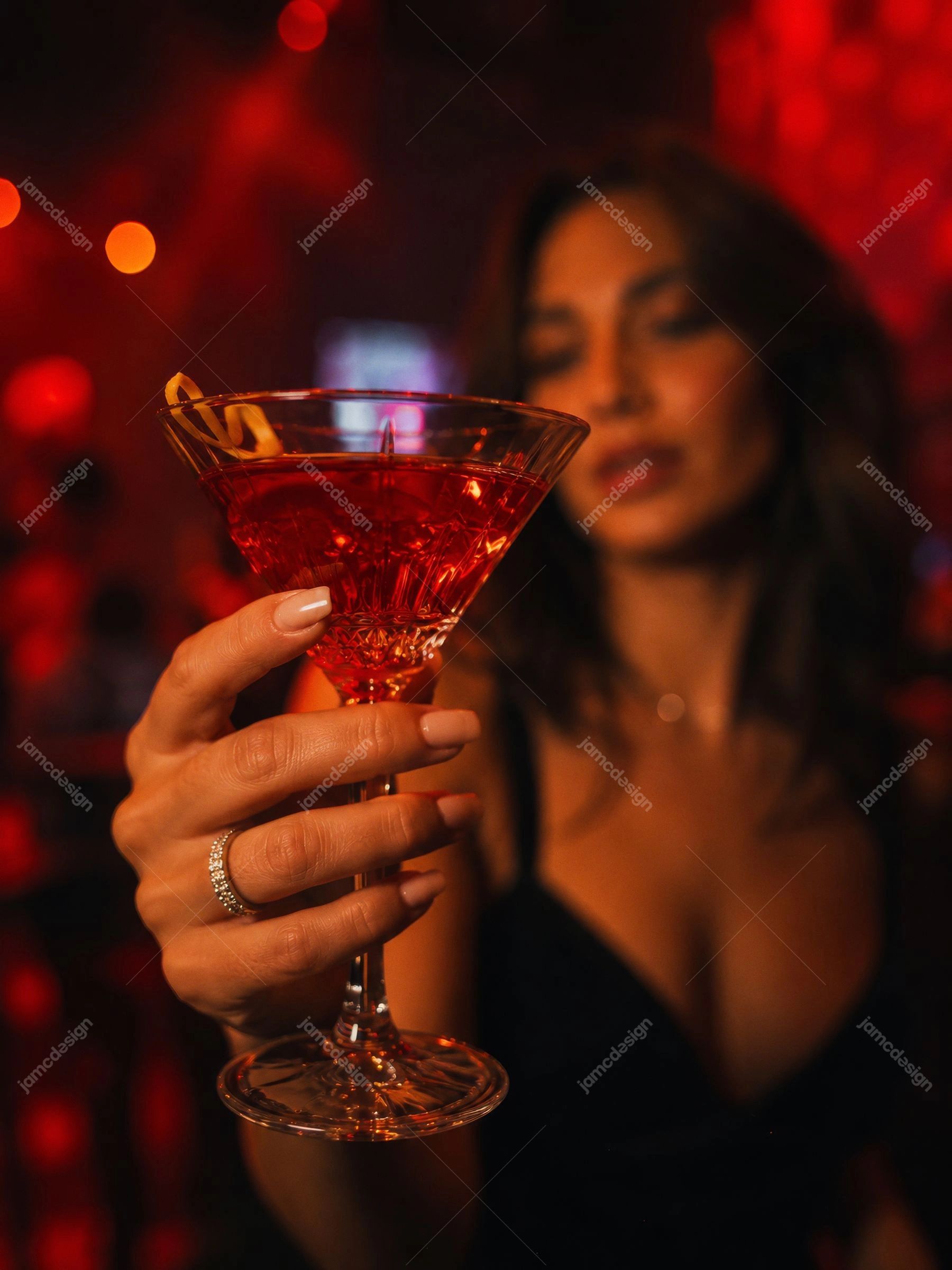 Foto De Mulher Com Martini Vermelho Em Bar Escuro. Foto JPG de uma mulher segurando um martini vermelho em um bar escuro