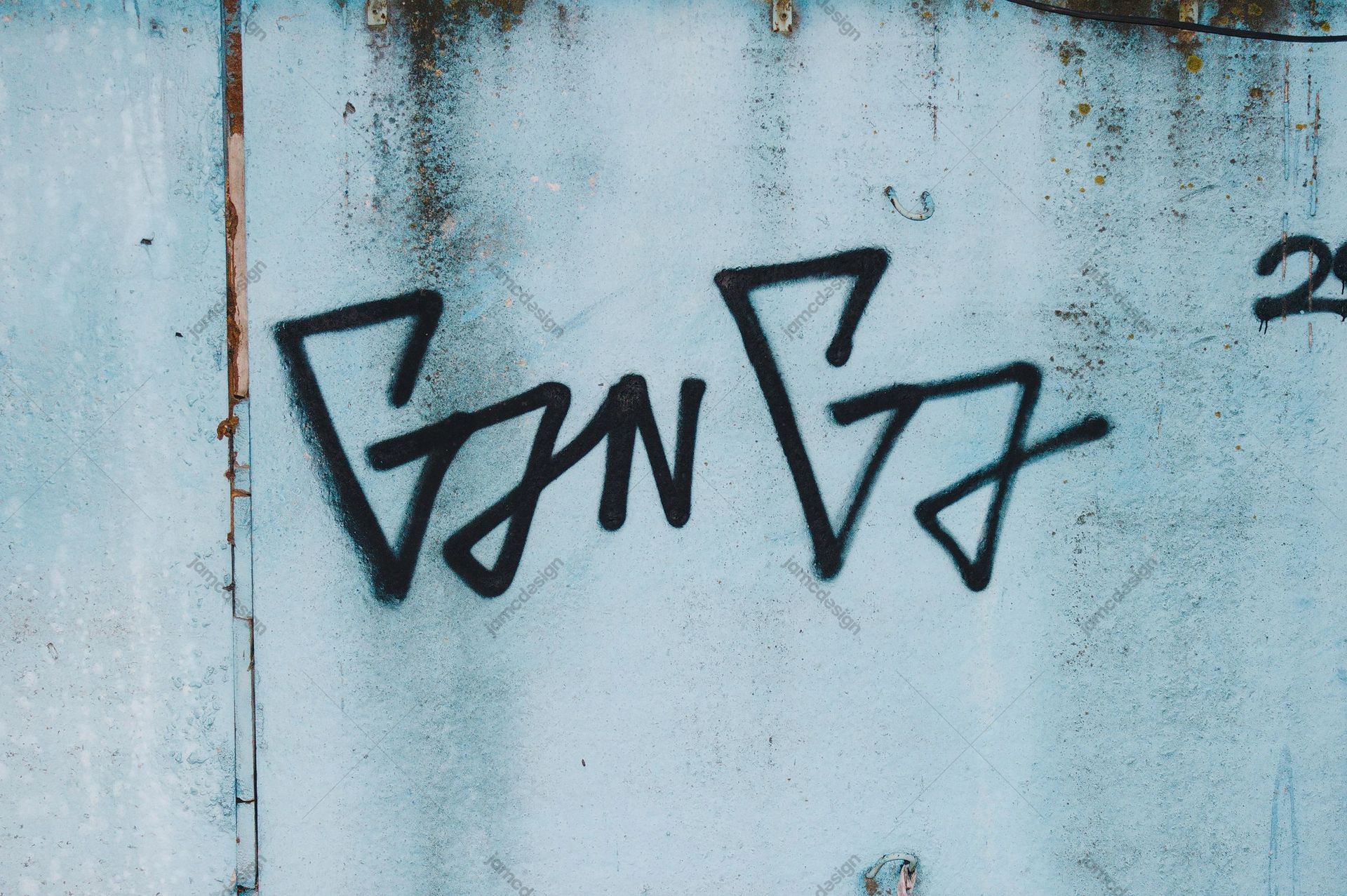 Pale Aqua Wall Texture With Black Graffiti. This JPG texture shows a pale aqua, weathered wall marked by bold black angular graffiti and scattered rust stains