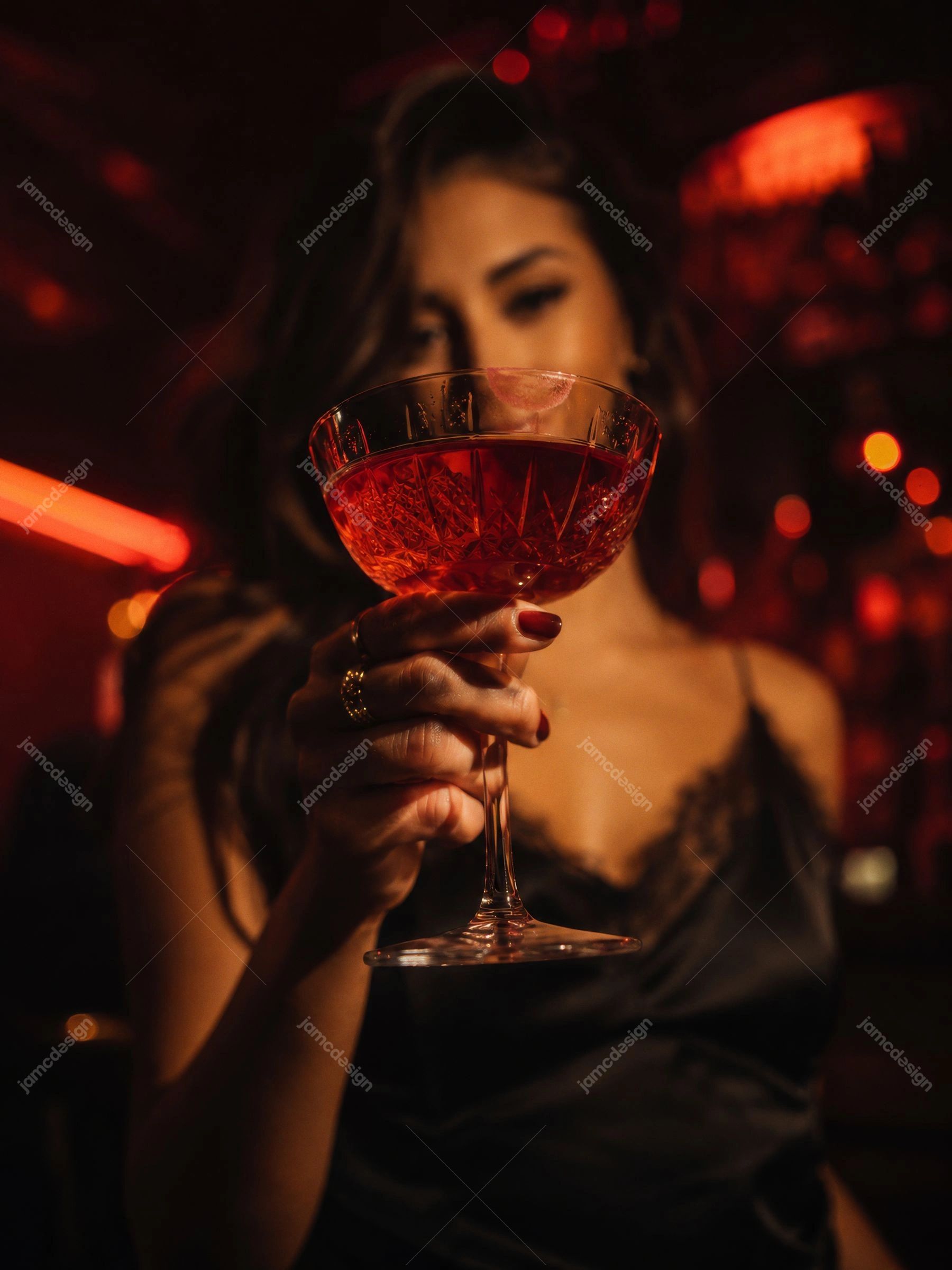 Photo En Gros Plan D’Un Cocktail Rouge En Discothèque De Luxe. Photo JPG d’une femme tenant un verre à cocktail rouge dans une discothèque de luxe sombre