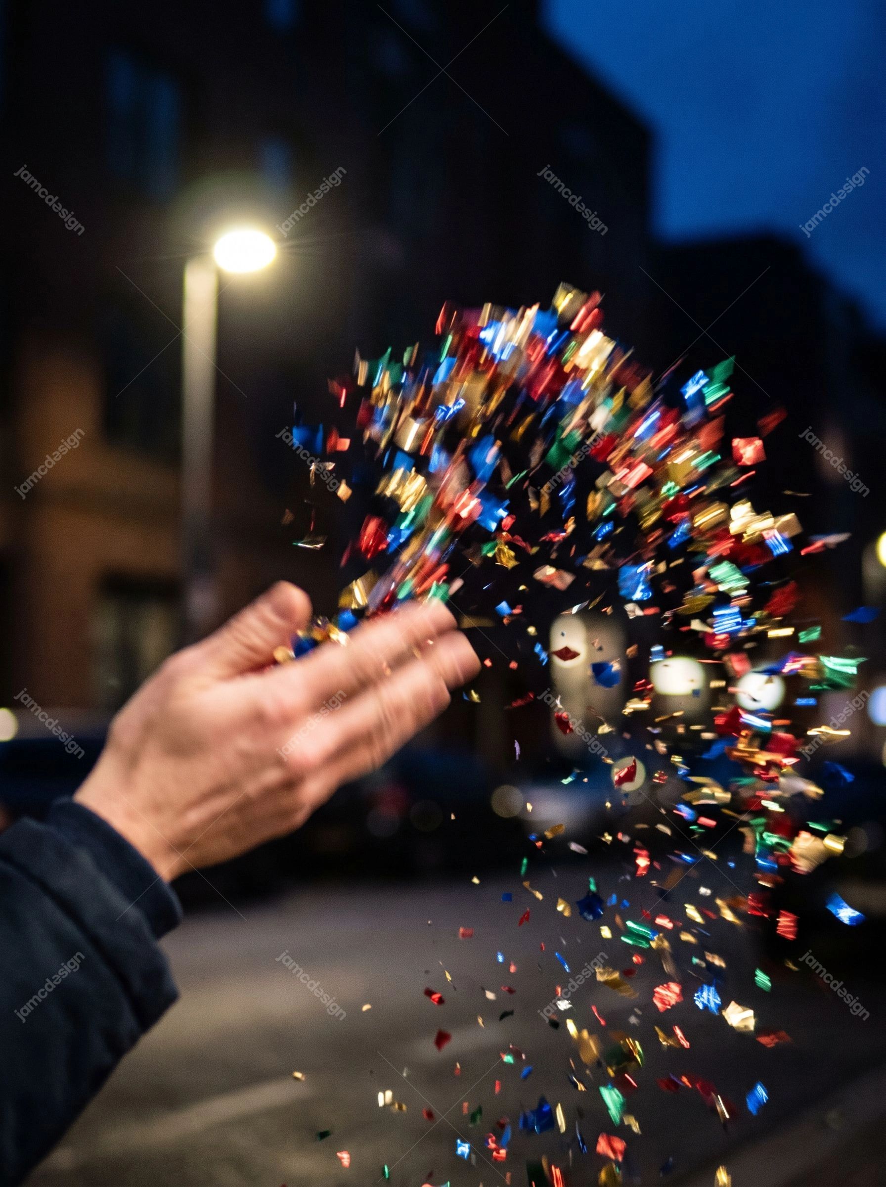 Hand Tossing Colorful Confetti At Night. Download this JPG photo of a hand tossing colorful confetti into the night