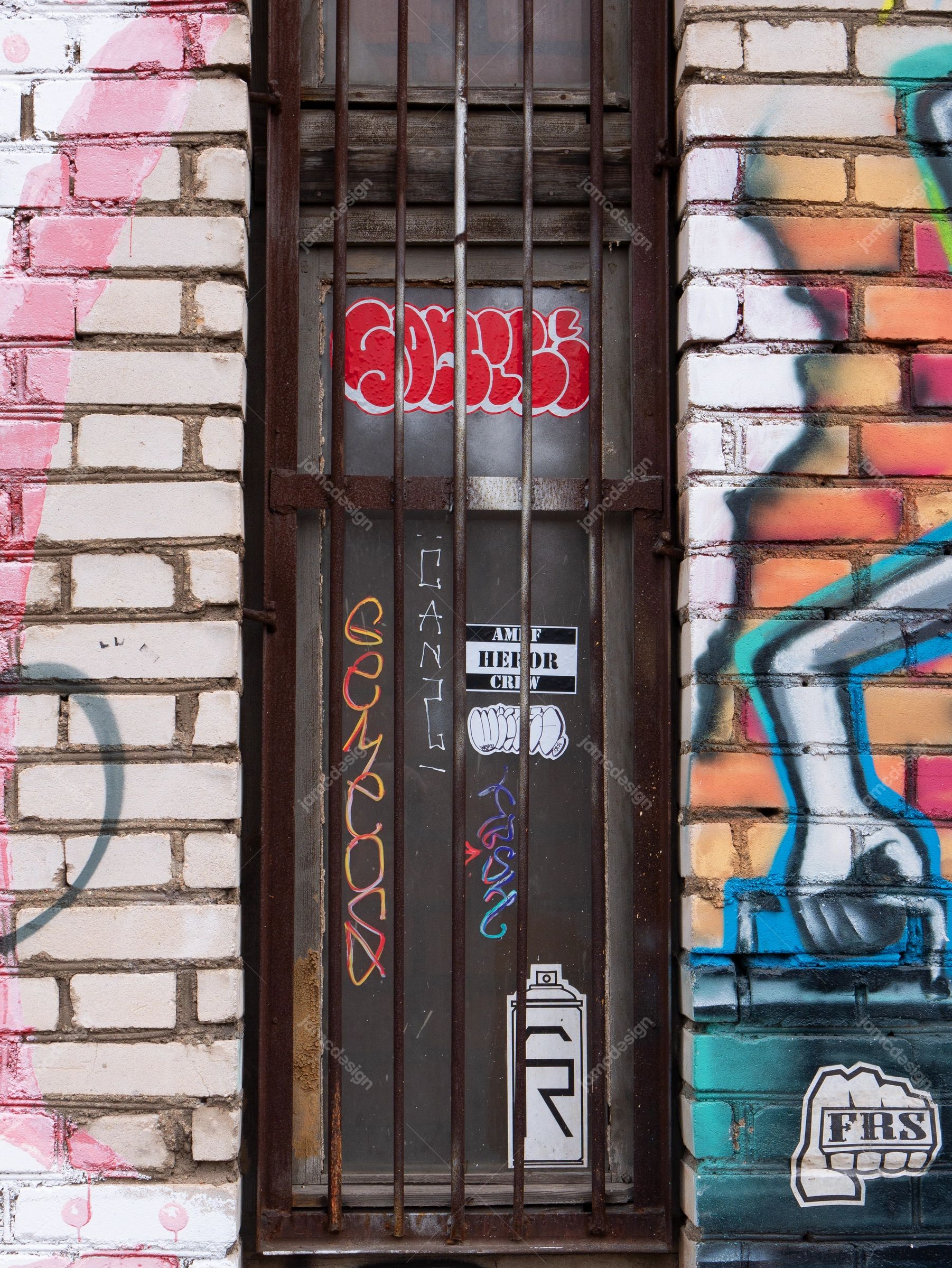 Urban Graffiti Brick Wall Texture PNG. This PNG texture shows a barred doorway set into a graffiti covered brick wall