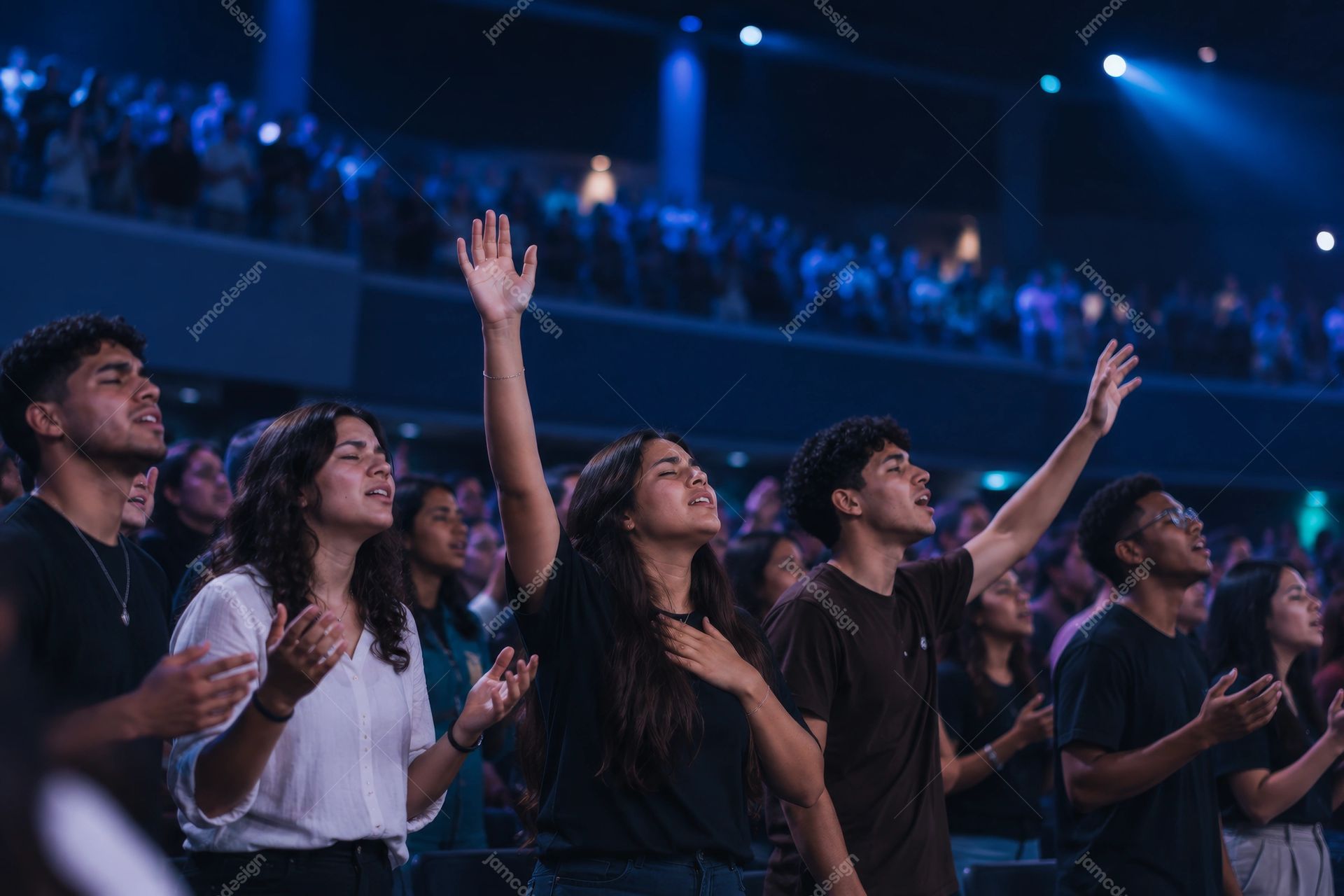 Youth Congregation Worshipping Under Blue Lights Photo. This PNG photo captures young people worshipping together, with raised hands