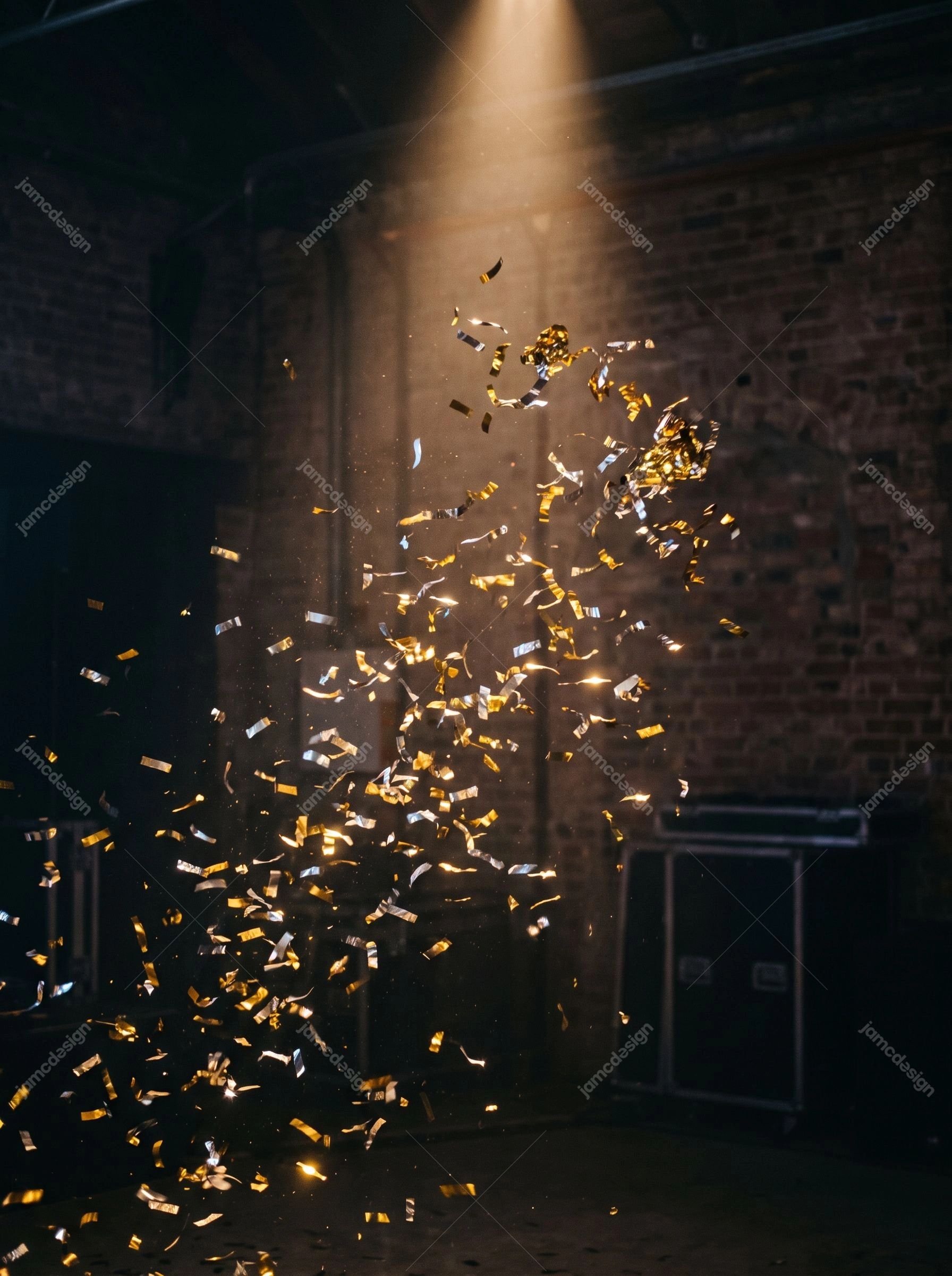 Gold And Silver Confetti Falling At A Party. This JPG photo shows gold and silver confetti falling through a warm spotlight in a dark brick venue