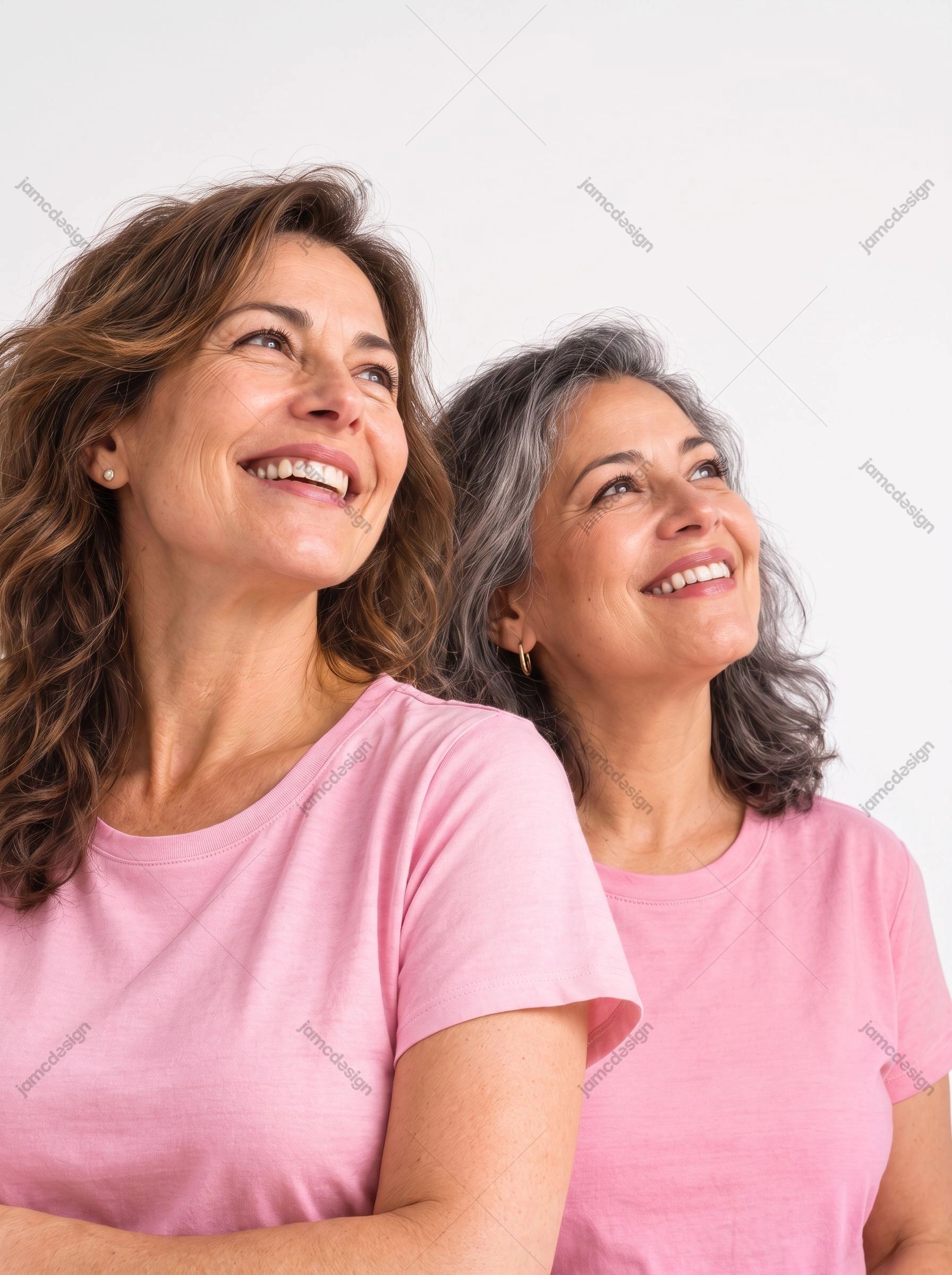 Close-Up Portrait Of Two Women In Pink Shirts. This JPG photo shows two smiling women in pink shirts, framed closely against a bright white background