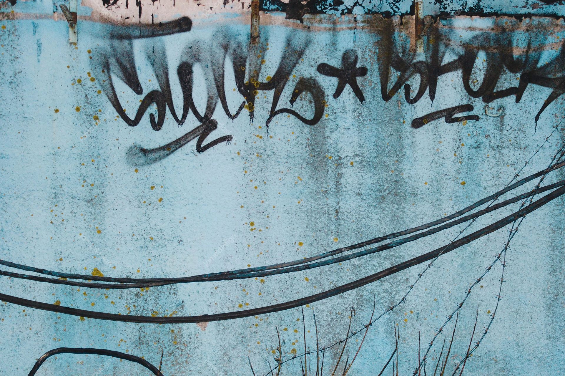 Blue Wall Texture With Graffiti And Overhead Wires. This JPG texture shows a weathered blue wall with black graffiti, overhead wires